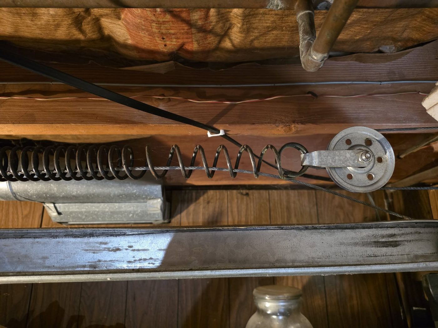 Extension spring and pulley on a garage door, ready for replacement