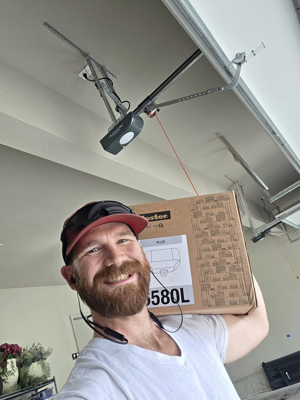 Zach Wallace carrying a new LiftMaster opener into a garage